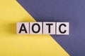 Word AOTC - American Opportunity Tax Crediton, wooden cubes, over yellow and blue background Royalty Free Stock Photo