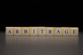 The word ARBITRAGE written on wooden cubes isolated on a black background Royalty Free Stock Photo