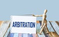 The word arbitration is written on a notebook, next to a wooden doll