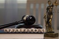 Word ARRAIGNMENT composed of wooden dices. Wooden gavel and statue of Themis in the background Royalty Free Stock Photo