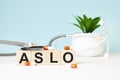 The word ASLO is written on wooden cubes near a stethoscope on a wooden background. Medical concept
