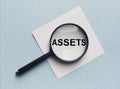 Word Assets on paper through magnifying glass on office table. Financial accounting. Money concept Royalty Free Stock Photo