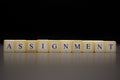 The word ASSIGNMENT written on wooden cubes isolated on a black background