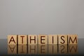 Word Atheism made of wooden cubes with letters on mirror surface