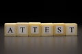 The word ATTEST written on wooden cubes isolated on a black background Royalty Free Stock Photo