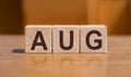 Word AUG on wooden cubes over orange wall background