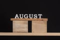 Word August made of wooden letters on black background. Front view. Summer calendar