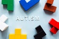 The word AUTISM on a blue background, with various colored blue cubes. World autism awareness day concept.