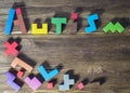 Word Autism built of wooden puzzles on a wooden background.