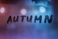 the word autumn handwritten on night wet window glass surface