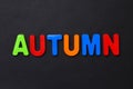 The word AUTUMN written in letters of the children`s magnetic alphabet on a black Royalty Free Stock Photo