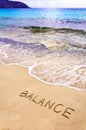 Word BALANCE written on beach sand, with sea waves in background