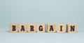 The word BARGAIN made from wooden cubes on blue background Royalty Free Stock Photo