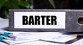 The word BARTER is written on a gray file folder next to documents. Business concept Royalty Free Stock Photo