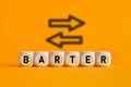 The word barter written on wooden cubes with exchange icons on yellow background. Trade in business market