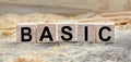 The word BASIC is written on wooden cubes. Wooden cubes lie on the table with sawdust and wooden blocks. Designed to promote your