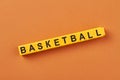 The word basketball written on yellow cubes against color background.