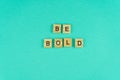 Word be bold. The phrase is laid out in wooden letters. Top view. Motivation. Blue background. Copy space