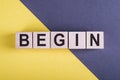 Word BEGIN on wooden cubes on yellow - gray background