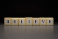 The word BELIEVE written on wooden cubes isolated on a black background Royalty Free Stock Photo