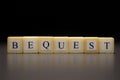 The word BEQUEST written on wooden cubes isolated on a black background Royalty Free Stock Photo