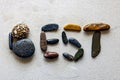 Word: BEST, written using colored stones on white sand Royalty Free Stock Photo