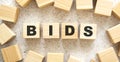 The word BIDS consists of wooden cubes with letters, top view on a light background Royalty Free Stock Photo