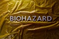 The word biohazard laid with silver letters on yellow crumpled plastic film background in flat lay composition at center Royalty Free Stock Photo