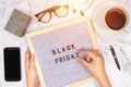 Word Black Friday on letter board on white marble desk background with coffee cup ,gift box and smart phone with blank screen
