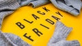 Word black friday on yellow background with sweaters around , shopping sale concept