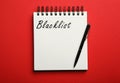 Word Blacklist written in notepad on red background, top view