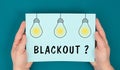 The word blackout is standing under lightbulbs, power cut out, uncertain energy supply Royalty Free Stock Photo