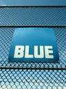 Word Blue on blue sign board on mesh fence