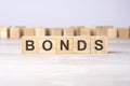 word bonds inscribed on wooden cubes lying on a light table. economy and investments concept.