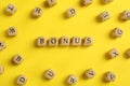 Word Bonus made of wooden cubes with letters on yellow background, flat lay Royalty Free Stock Photo