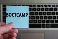 Word BOOTCAMP on sticky note hold in hand on keyboard background