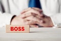 The word boss written on a wooden block in front of a businessman