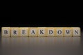 The word BREAKDOWN written on wooden cubes isolated on a black background