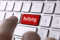 word bullying on the computer's gray keyboard. The concept of harassment intimidation and humiliation in the network