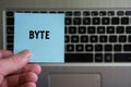 Word BYTE on sticky note hold in hand on keyboard background Royalty Free Stock Photo