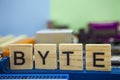 Word BYTE on the wooden blocks with computers mainboard background. Information technology background with mainboard.