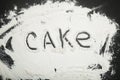 Word cake written on white flour, black background