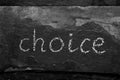 The word CHOICE written with chalk on black stone