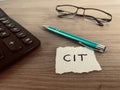 Word CIT with pen, calculator and glasses on office desk, polish corporate income tax concept