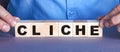 The word CLICHE is made up of wooden cubes by a man. Business concept