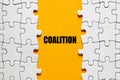 The word coalition between the jigsaw puzzle pieces. Alliance, cooperation and collaboration in business or politics