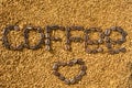 The word coffee and heart from the coffee beans on the background of scattered instant coffee. Texture.