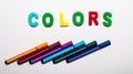 The word COLORS is made up of bright letters on a white background, multicolored markers lie nearby
