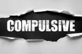 Word COMPULSIVE displayed in bold distressed font on torn paper background, symbolizing obsession, uncontrollable behavior, Royalty Free Stock Photo