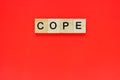 Word cope. Top view of wooden blocks with letters on red surface Royalty Free Stock Photo